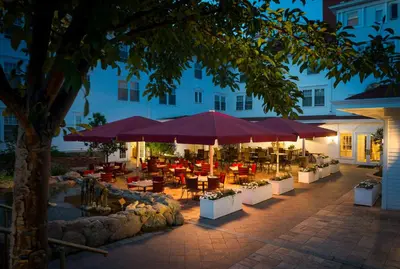 a patio with tables and umbrellas in front of a building at The Stanley Hotel in Estes Park