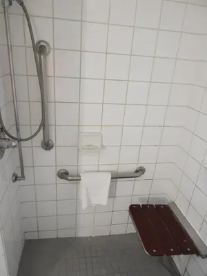 a bathroom with a bench and a toilet paper dispenser at Super 8 by Wyndham Westminster Denver North in Westminster