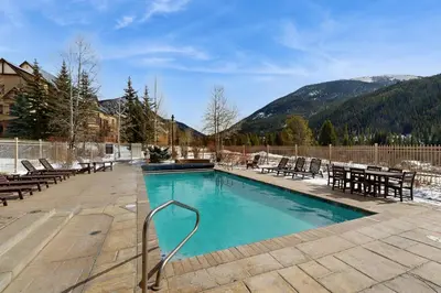 a swimming pool with chairs and a table and mountains at Red Hawk Lodge 2254 in Keystone