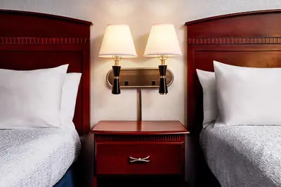 a hotel room with two beds and a table with two lamps at Hampton Inn Longmont in Longmont