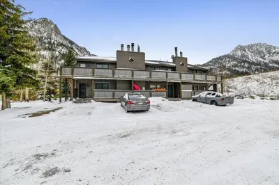 two cars parked in front of a building in the snow at Forest Park F Condo in Frisco