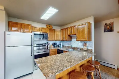 a kitchen with a white refrigerator and wooden cabinets at Buffalo Village 402 in Silverthorne