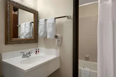 a bathroom with a sink and a mirror and a shower at Days Inn by Wyndham Fort Collins in Fort Collins