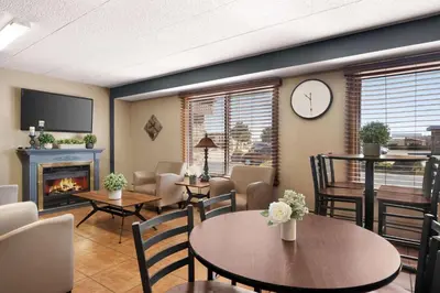 a living room with a table and chairs and a clock at Days Inn by Wyndham Fort Collins in Fort Collins