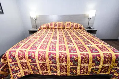 a bed in a hotel room with a colorful bedspread at Belcaro Motel in Denver
