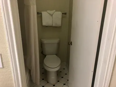 a bathroom with a toilet and towels on a wall at Americas Best Value Inn Denver in Denver