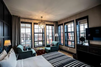 a hotel room with a bed and chairs and windows at The Ramble Hotel in Denver
