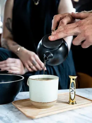 a person stirring a cup of coffee on a table at The Ramble Hotel in Denver