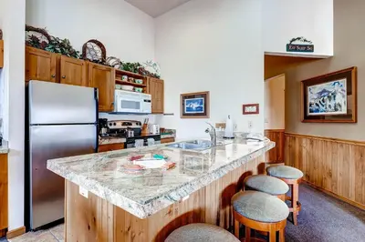 a kitchen with a refrigerator and a counter with stools at Jackpine 8021 in Keystone
