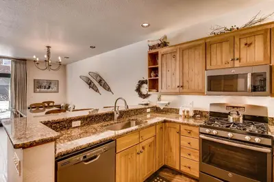 a kitchen with wooden cabinets and a sink and a stove at Ski Tip Townhomes 8713 in Keystone