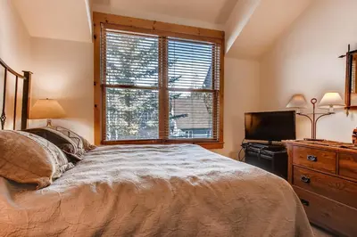 a bedroom with a bed and a television and a window at Ski Tip Townhomes 8713 in Keystone