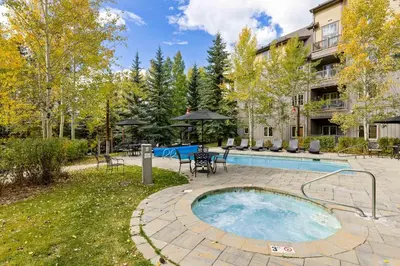 a backyard with a pool and a patio with tables and chairs at 8577 Expedition Station Condo in Keystone