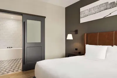 a bedroom with a bed and a door and a bath tub at Origin Red Rocks, a Wyndham Hotel in Golden
