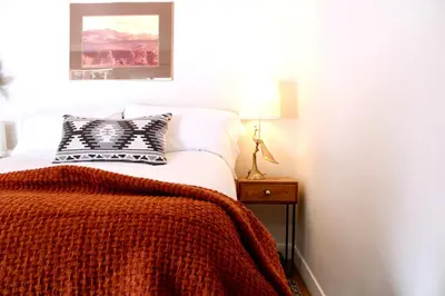 a bedroom with a bed with an orange blanket on it at Kinnikinnik Motor Lodge in Estes Park