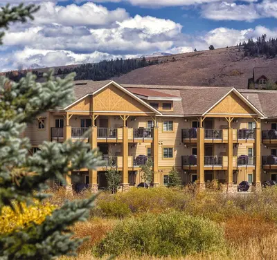 a large apartment building with a hill in the background at WorldMark Granby - Rocky Mountain Preserve in Granby