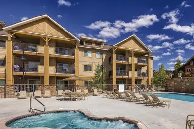 a large apartment building with a swimming pool and chairs at WorldMark Granby - Rocky Mountain Preserve in Granby
