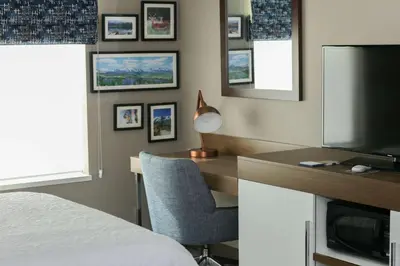 a bedroom with a bed and a desk with a television at Hampton Inn & Suites Lafayette in Lafayette