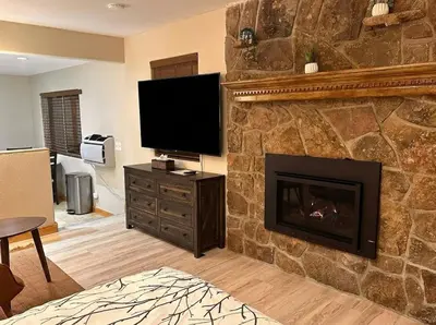 a living room with a stone fireplace with a flat screen tv at Stonebrook Resort - Adult Only in Estes Park