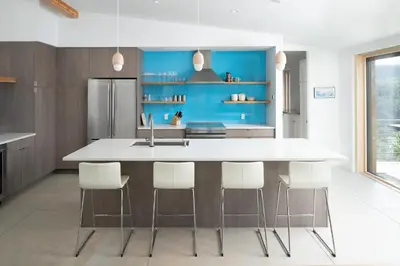 a kitchen with a large white island with white chairs at Timberline Haus Home in Nederland