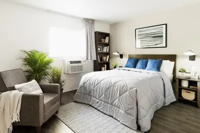 a bedroom with a bed and a chair and a window at InTown Suites Extended Stay Denver - Englewood in Englewood