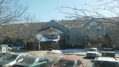 a large house with cars parked in a parking lot at InTown Suites Extended Stay Denver - Englewood in Englewood