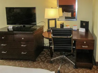 a desk with a dresser and a desk with two chairs at Clarion Inn in Fort Collins