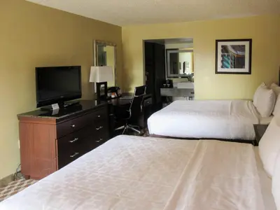 a hotel room with two beds and a desk with a television at Clarion Inn in Fort Collins
