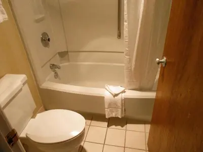 a bathroom with a tub and a toilet and a sink at Clarion Inn in Fort Collins