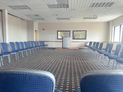 an empty lecture room with blue chairs and a podium at Clarion Inn in Fort Collins