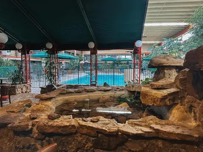 a large stone fountain in a building with a swimming pool at Clarion Inn in Fort Collins