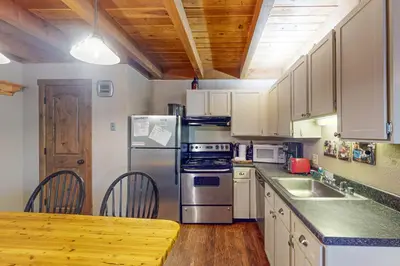 a kitchen with white cabinets and a table and a refrigerator at Lodgepole Landing in Silverthorne