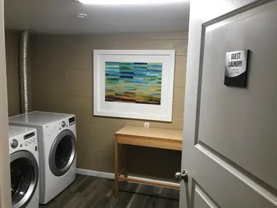a laundry room with a washing machine and a painting at Lamplighter Motel in Longmont