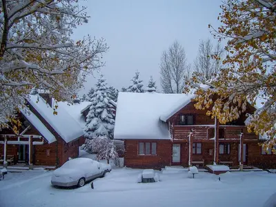 a house covered in snow with a car parked in front at Rams Horn Village Resort in Estes Park
