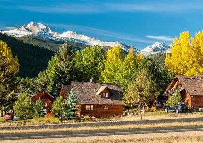a group of houses and trees with mountains in the background at Rams Horn Village Resort in Estes Park