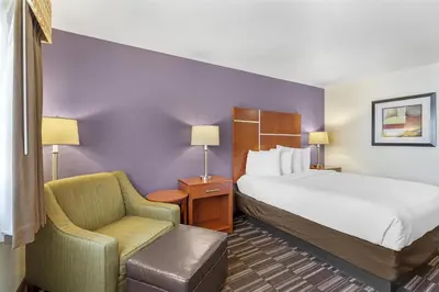 a hotel room with a bed and a chair at Best Western Firestone Inn & Suites in Longmont