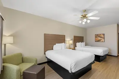 a hotel room with two beds and a chair at Best Western Firestone Inn & Suites in Longmont