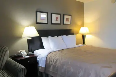 a hotel room with a bed with two lamps and a chair at Quality Inn Longmont in Longmont