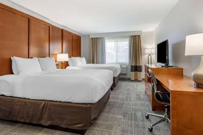 a hotel room with two beds and a desk and a television at Comfort Suites Golden West on Evergreen Parkway in Evergreen
