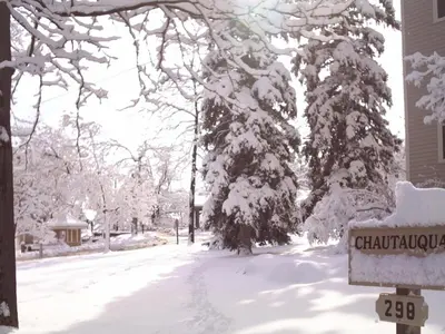 a snow covered street with a sign in front of a house at Colorado Chautauqua Cottages in Boulder