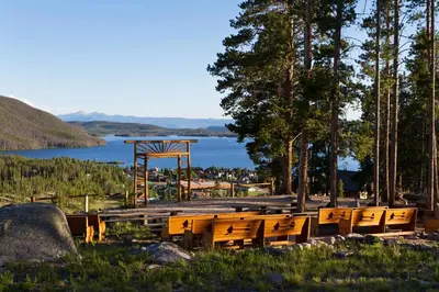 a group of wooden benches sitting next to a lake at Grand Lake Lodge in Grand Lake