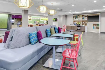 a living room with a couch and tables and chairs at Home2 Suites By Hilton Fort Collins in Fort Collins