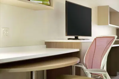 a room with a desk with a monitor and a chair at Home2 Suites By Hilton Fort Collins in Fort Collins
