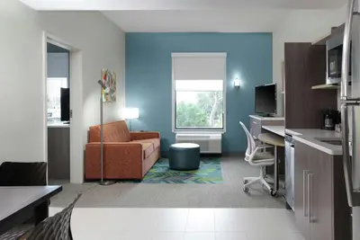 a blue living room with a couch and a desk at Home2 Suites By Hilton Fort Collins in Fort Collins