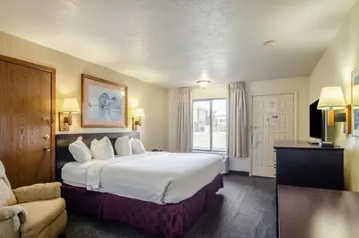 a hotel room with a large bed and a chair at Americas Best Value Inn & Suites Ft Collins E at I-25 in Fort Collins