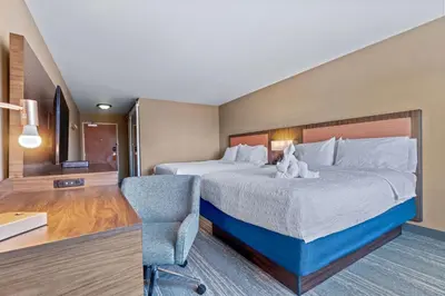 a hotel room with a large bed and a chair at Hampton Inn & Suites Greeley in Greeley