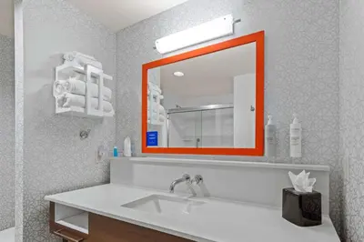 a bathroom with an orange mirror and a sink at Hampton Inn & Suites Greeley in Greeley