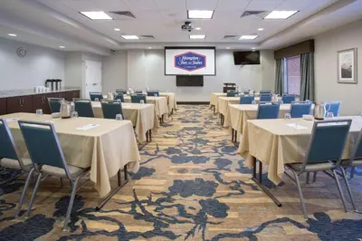 a conference room with tables and chairs and a screen at Hampton Inn & Suites Denver Airport / Gateway Park in Denver