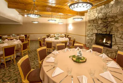a dining room with tables and chairs and a fireplace at Winter Park Mountain Lodge in Winter Park