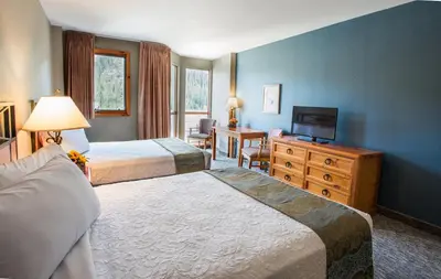 a hotel room with two beds and a television at Winter Park Mountain Lodge in Winter Park