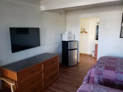 a bedroom with a bed and a dresser with a tv at Americas Best Value Inn Greeley in Evans
